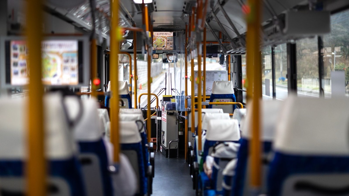 日本の路線バスの車内。白と青の空席と黄色い手すりが並び、奥に運賃箱が見える