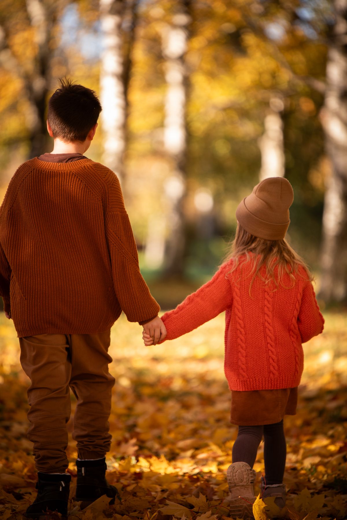 落ち葉の道を並んで歩く子ども2人の後ろ姿。同じ場面にいても、消耗のしかたは子どもによって違う